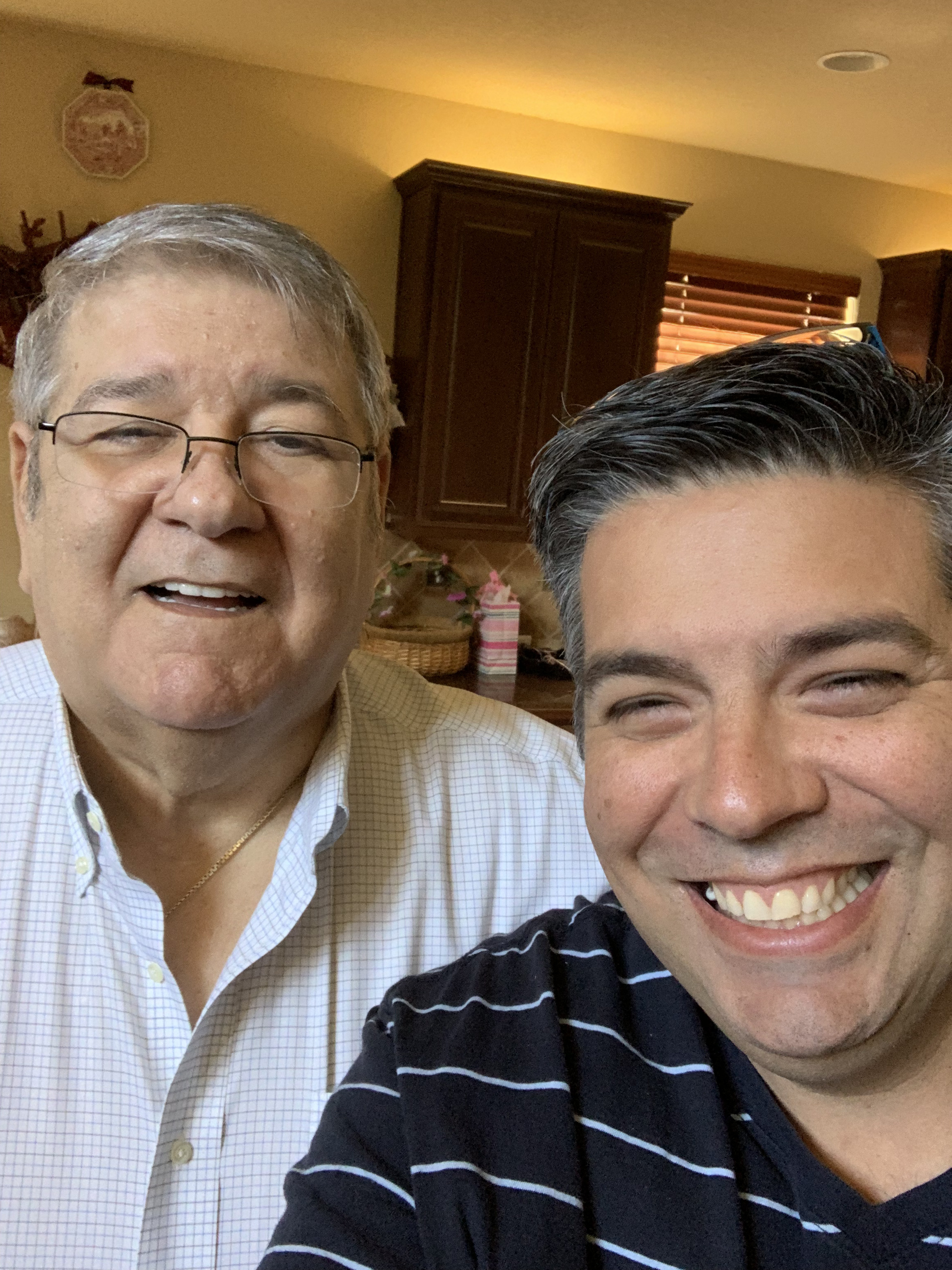 Paul Trevino smiling next to his dad, the first storyteller, in a sunlit kitchen.